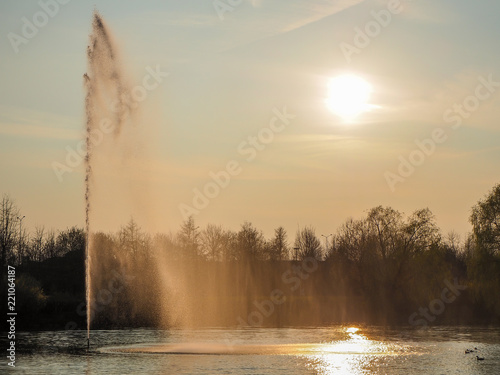 Beautiful view of a fountain in a public park at sunset in backlight
