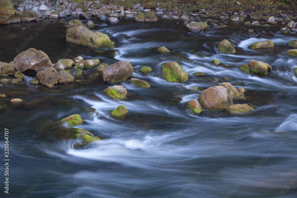Fast streaming mountain river with rocks in it Fast streaming mountain river with rocks in it