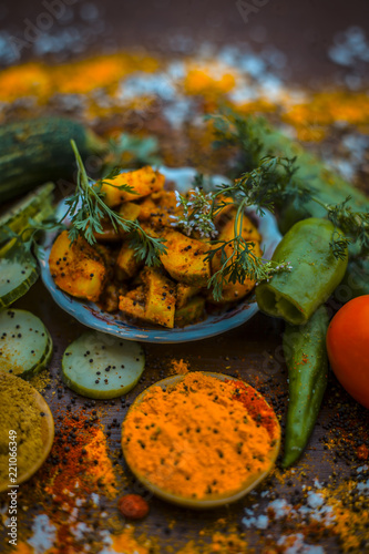 Close up of India's or Asia's popular pickle i.e. Indian pickling cucumber pickle or Indian styled cucumber pickle or salad on wooden surface with all necessary ingredients in dark gothic colors. photo