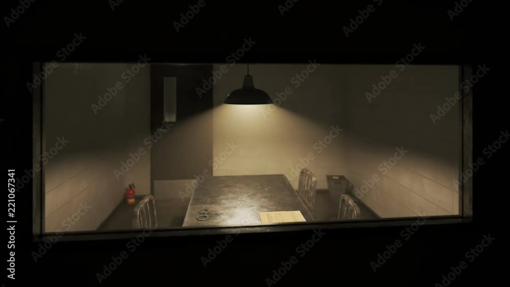Dark, empty interrogation room seen through the one-way mirror ...