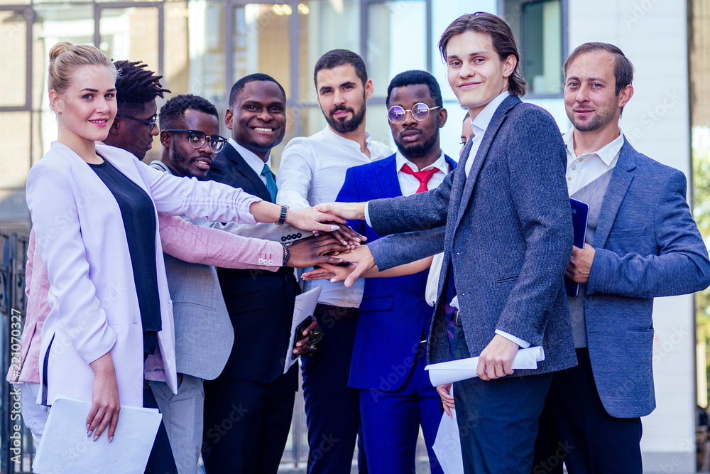 a group of nine multinational people businesswomen and business men in stylish suits work in a team outdoors. teamwork and success concept