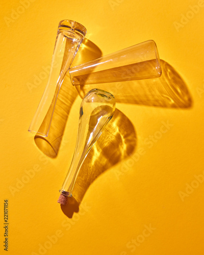 Empty glass bottles lie on a yellow background with shadows and reflection. Top view. photo