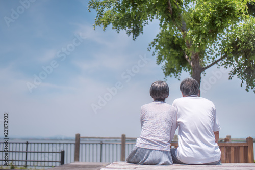 公園のベンチに座るシニア夫婦の後ろ姿