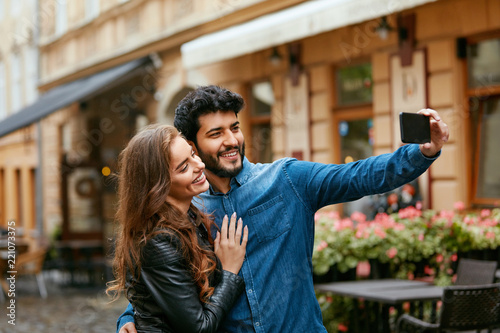 Couple Using Phone On Street, Taking Photos Or Video Calling © puhhha