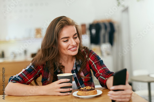 Happy Woman Using Phone In Cafe