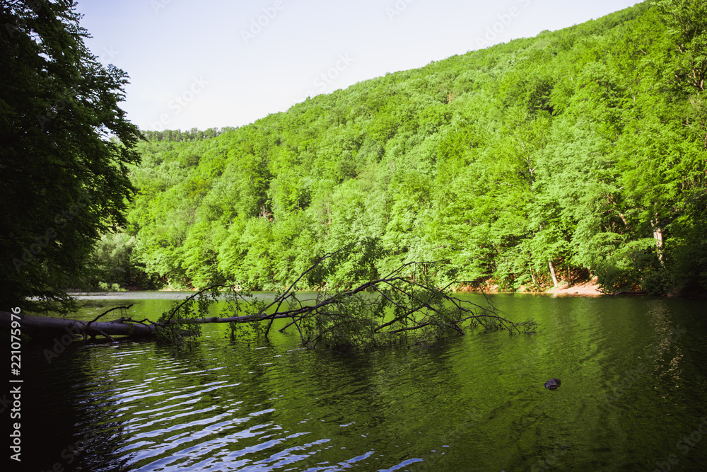 The Green Lake of Hamori in Lillafure near Miskolc, Hungary. Spring landscape with sunrays covering the mountains. The solar path on the water The Green Lake of Hamori in Lillafure near Miskolc, Hungary. Spring landscape with sunrays covering the mountains. The solar path on the water