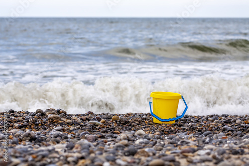 Lonely bucket at the gravel beach with ocean background photo