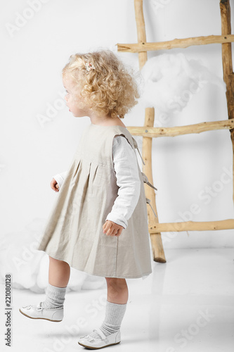 Portrait of a little girl near the ladder in the midst of clouds on a white background