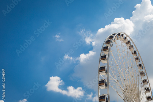 White big Ferris wheel with blue sky sharp clouds