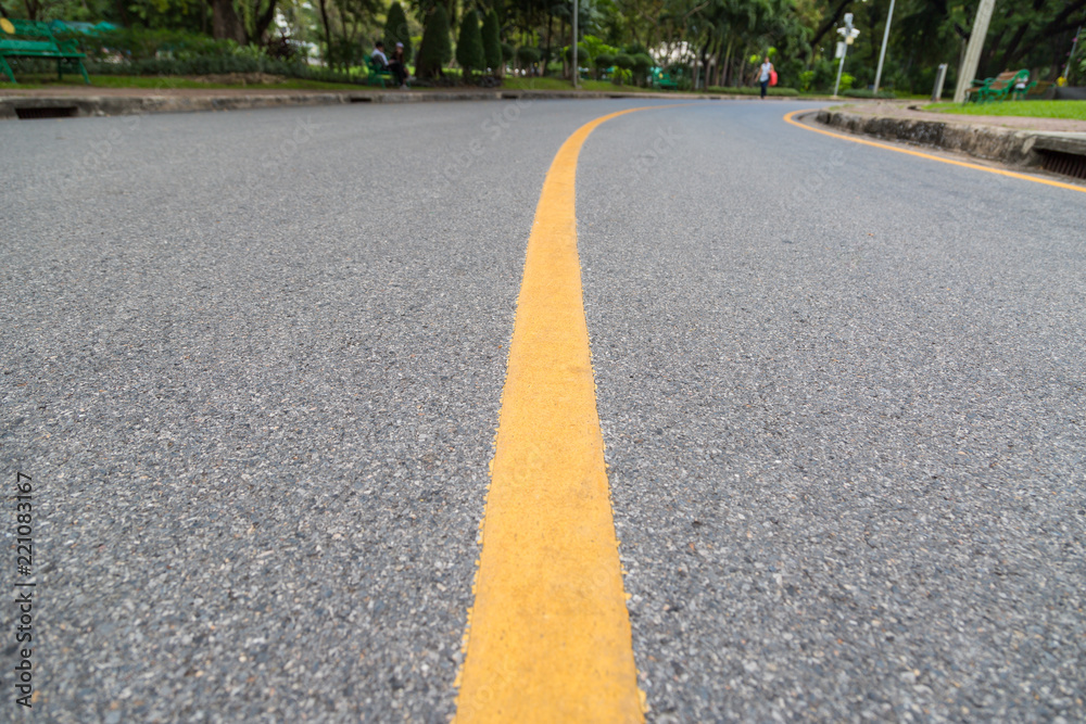 Close up of yellow line on the public park with people exercise and cycling for good health background Close up of yellow line on the public park with people exercise and cycling for good health background
