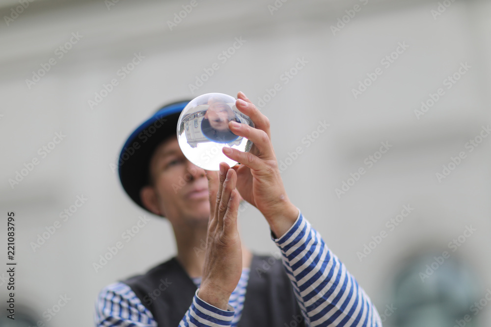 Transparent magic ball with reflection in the hands of a clown Transparent magic ball with reflection in the hands of a clown