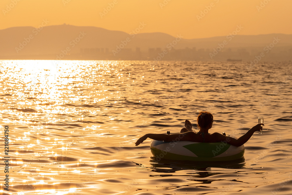 Man in the sea with a laptop at sunset