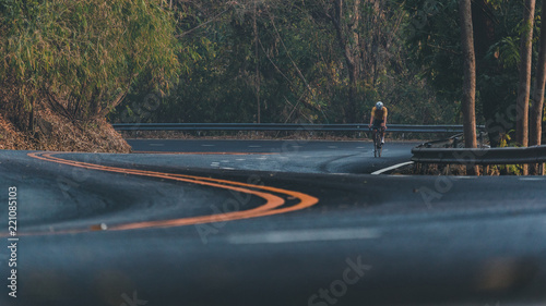 Asian man is cycling road bike. morning ride uphill on the road.