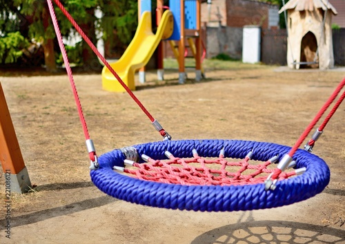 Close-up of colorful blue-red nest swing seat in the playground.