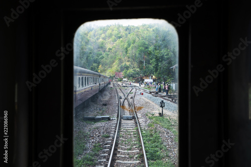 looking outside from local train window, see railroad and train station platform nestle to the mountain.