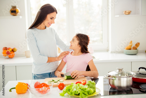 Beautiful charming mom and her small little daughter cooking gre