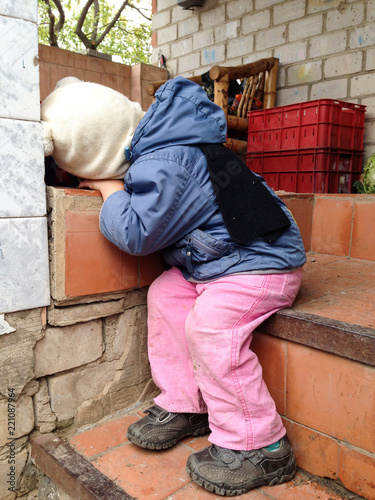 Happy village boy in blue jacket and pink pants fell asleep on steps of his house, waiting for his parents. Life in countryside