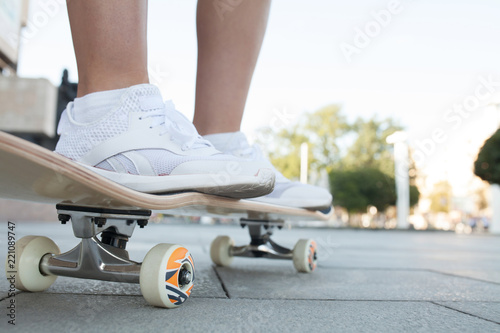 Young woman legs on skateboard outdoors active lifestyle. Close up.