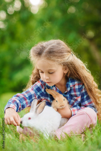 Girl is feeding a cute little rabbit, outdoor, summer day