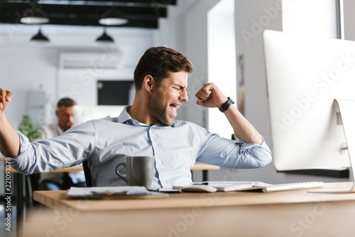 Joyful male manager rejoices while using compute