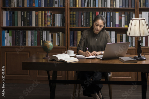 Elegant mature woman using laptop in study photo