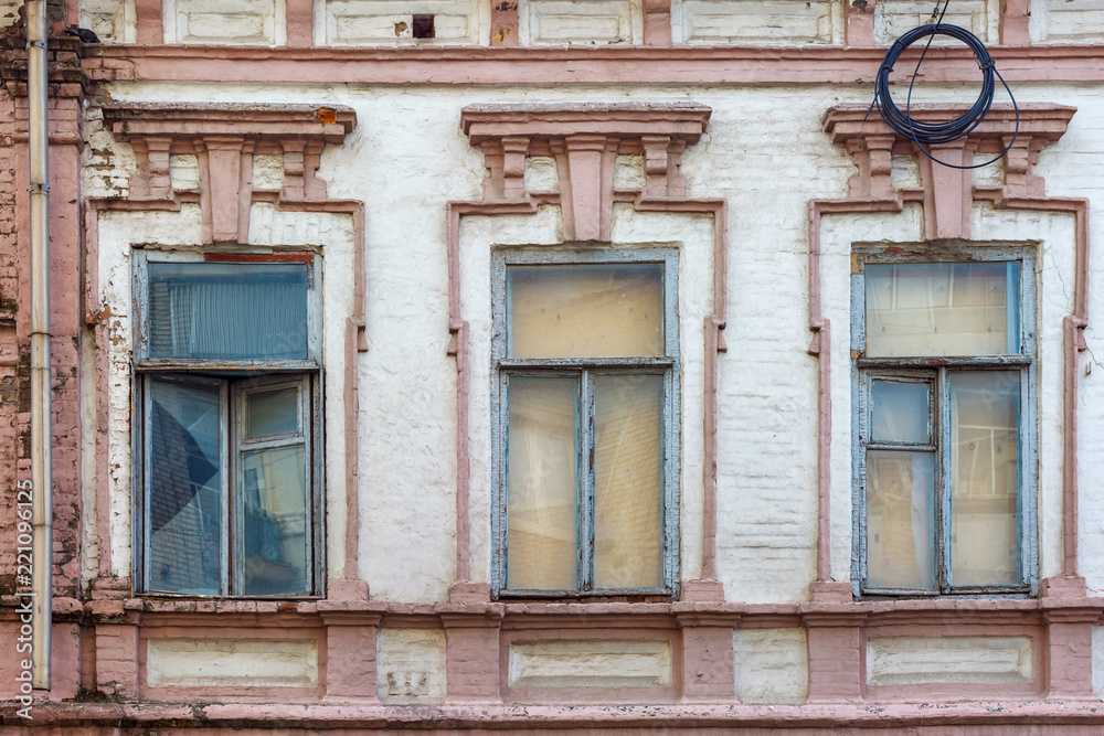 The three old-fashioned windows on the facade of the old brick building The three old-fashioned windows on the facade of the old brick building
