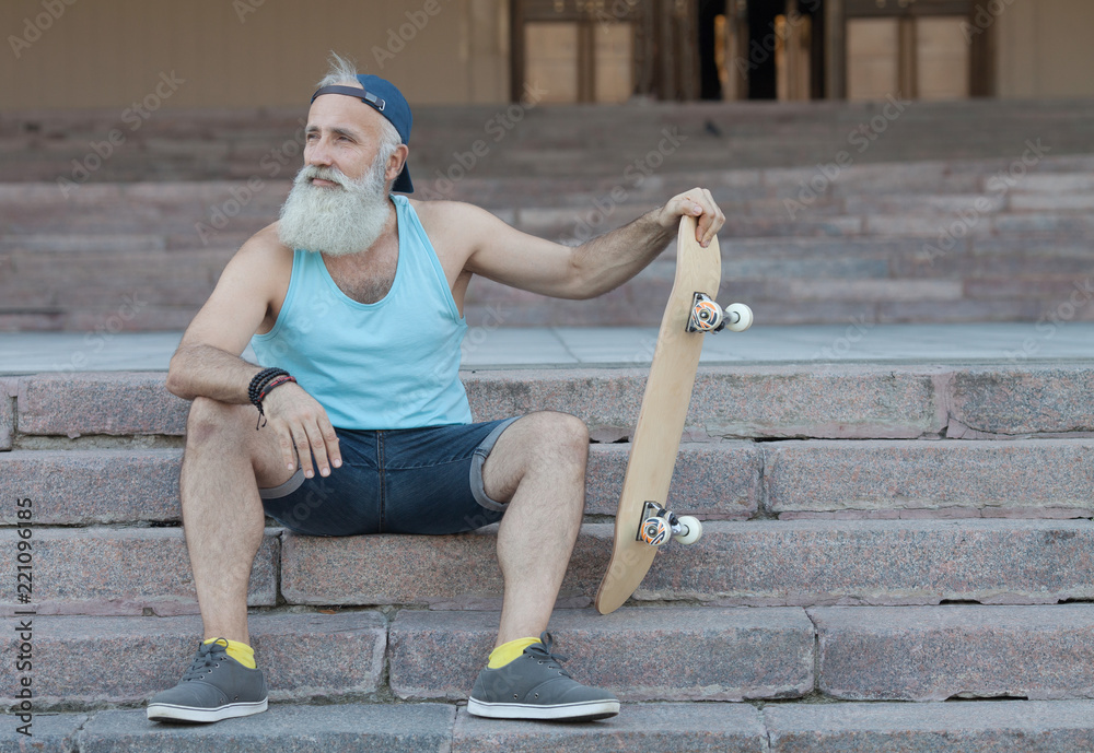 Happy bearded old man. The concept of life satisfaction. Portrait of a  positive gray-haired man with a skateboard. Winner concept. Stock Photo |  Adobe Stock