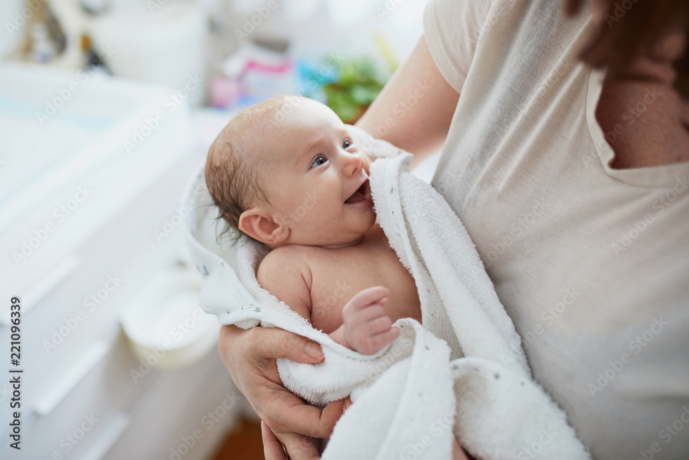Mother holding baby wrapped in towel after bath - obrazy, fototapety, plakaty 