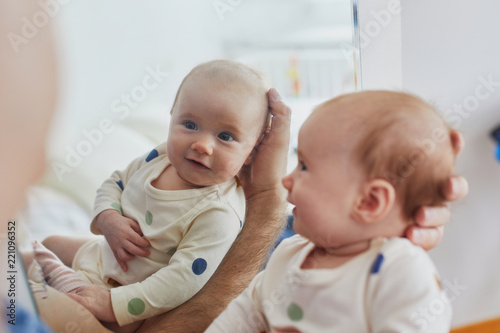 Baby looking at her reflection in mirror and smiling