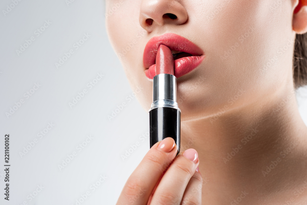 partial view of girl applying pink lipstick,  isolated on white