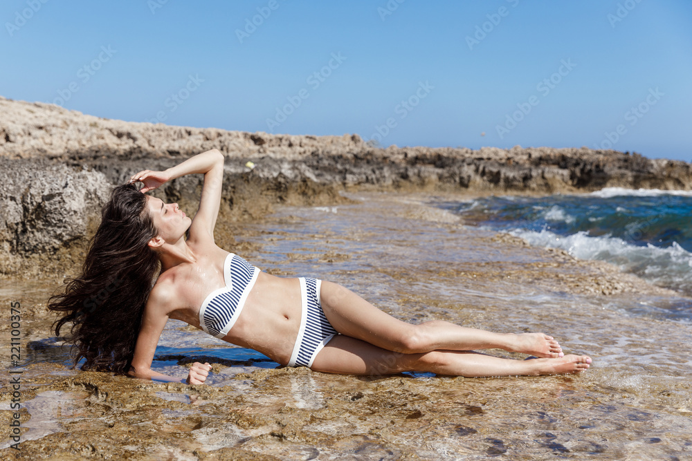 Girl with striped bathing suit on the seashore Girl with striped bathing suit on the seashore