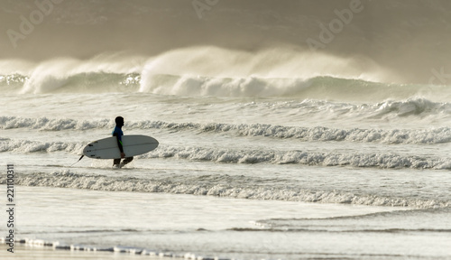 Surfer approaches Waves, Fistral Beach, Cornwall