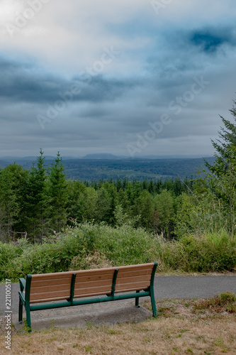 Empty bench overlooking forests and mountains on a stormy day