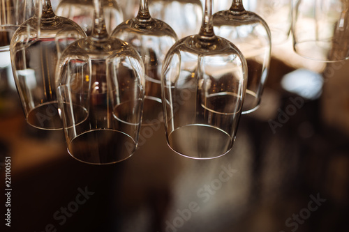 Absolutely clean. Close up of clean wine glasses hanging upside down while being ready for usage © Viacheslav Yakobchuk