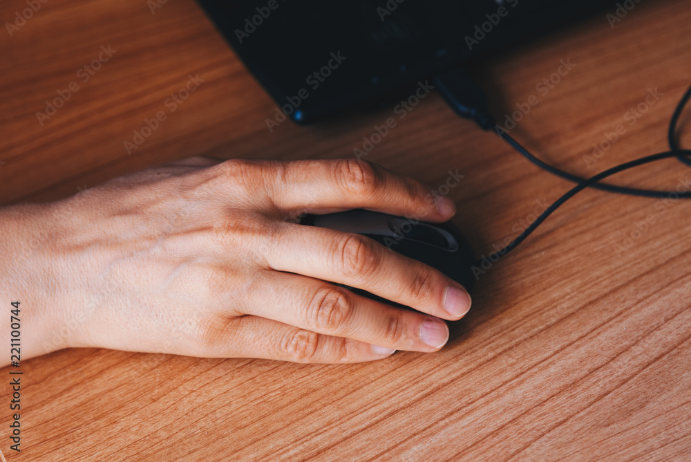 A woman's hand using mouse laptop - Cause tendinitis disease concept.