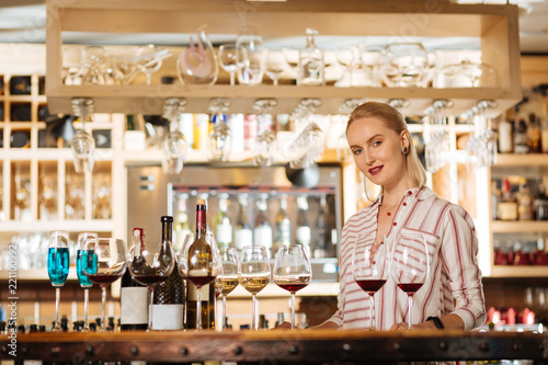 Wine bar. Beautiful attractive woman standing at the counter while being ready to taste the wine