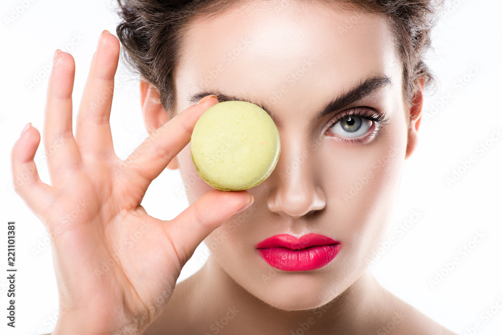elegant girl holding green macaron in front of eye, isolated on white elegant girl holding green macaron in front of eye, isolated on white