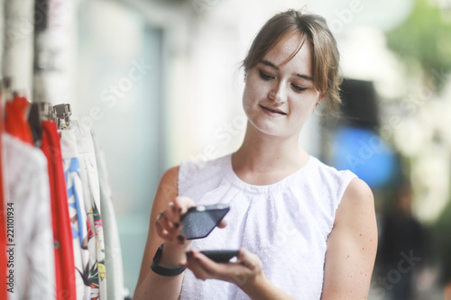 Junge Frau kauft mit Handy bargeldlos
