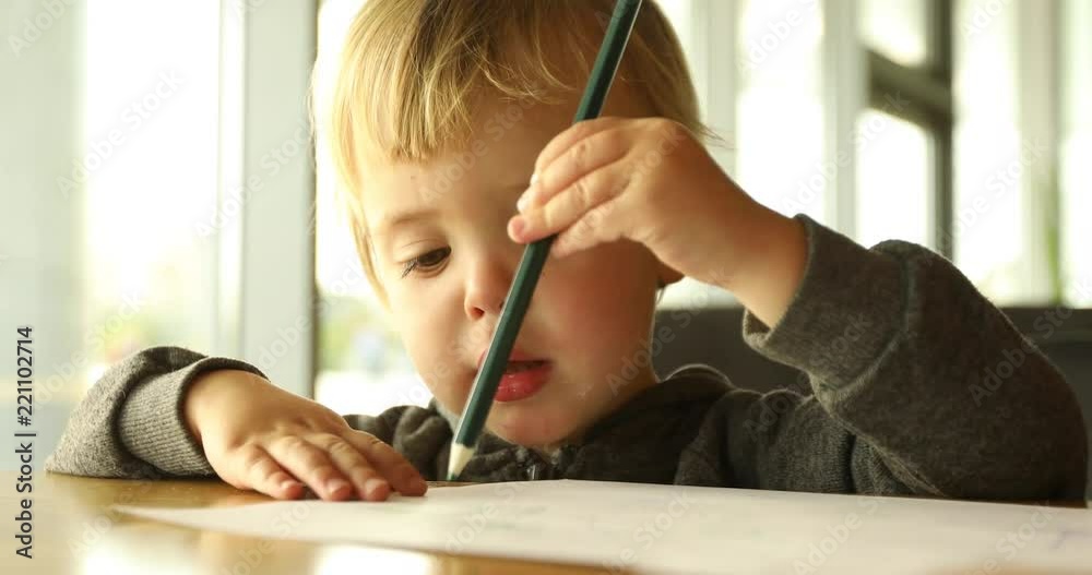 Child enthusiastically draws with on a piece of paper. Preschool education Baby boy smiling Child enthusiastically draws with on a piece of paper. Preschool education Baby boy smiling