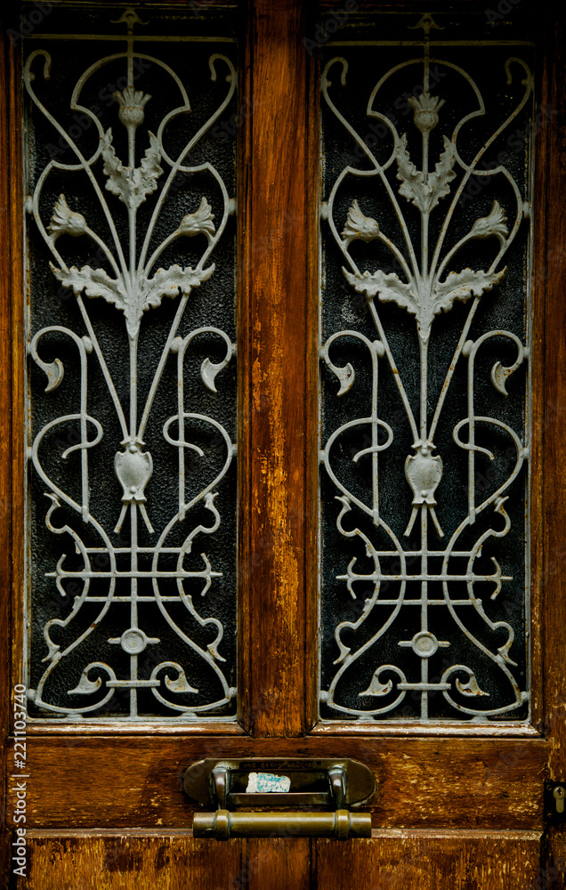 Old wooden door with stylish forged pattern and metallic handle Old wooden door with stylish forged pattern and metallic handle