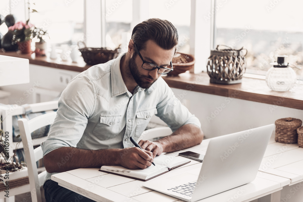 Young Business Man Sitting in Cafe taking Notes Young Business Man Sitting in Cafe taking Notes