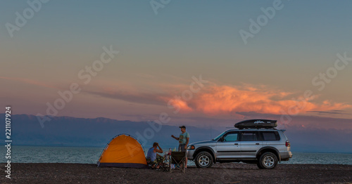 tourists by car with a tent on the lake shore