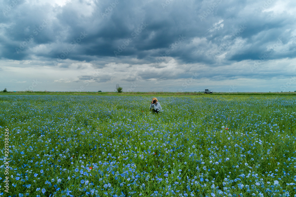 summer travel concept from front side of asian man traveler and photographer with black hair during take photo to flower field with sunny and soft focus background summer travel concept from front side of asian man traveler and photographer with black hair during take photo to flower field with sunny and soft focus background