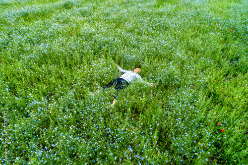Young beautiful woman relaxing in the field with flowers. Overhead view.