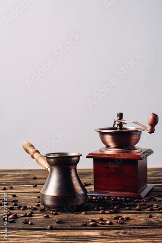 vintage cezve and coffee grinder with coffee beans on rustic wooden table