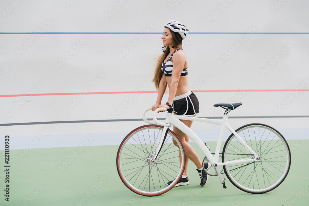 Cycling and fitness. Young beautiful fit woman with perfect body in  sportswear with the bicycle outdoors on the track. Sportive and healthy  lifestyle, cyclist working out, training, fashion, beauty. Stock Photo