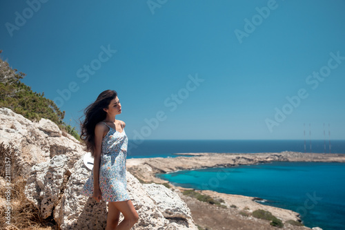 Girl on the edge of a cliff overlooking the sea in a dress