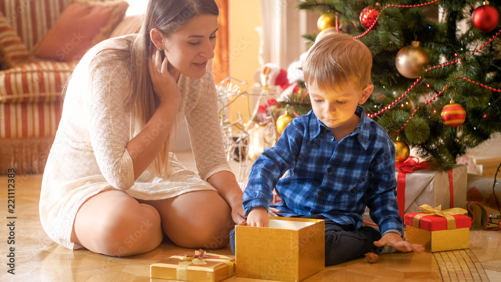 Little 3 years old toddler boy opens Christmas gift box and taking out a toy Little 3 years old toddler boy opens Christmas gift box and taking out a toy