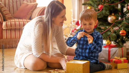Adorable smiling toddler boy looking at toy he received as gift for Christmas