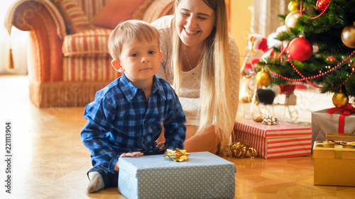 Portrait of smiling happy boy received Christmas present from Santa at morning